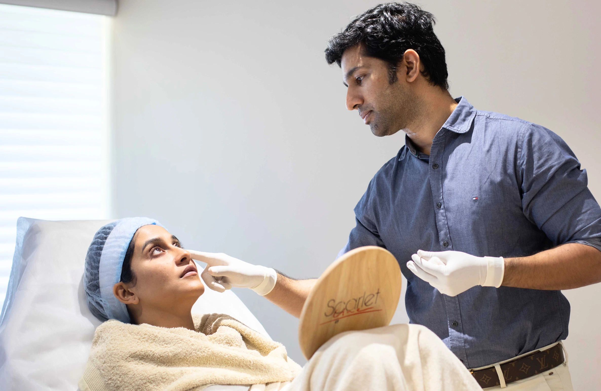 A dermatologist examining a patient’s skin during consultation, representing Celebrity Dermatologists in Hyderabad Treatments Stars Swear By.