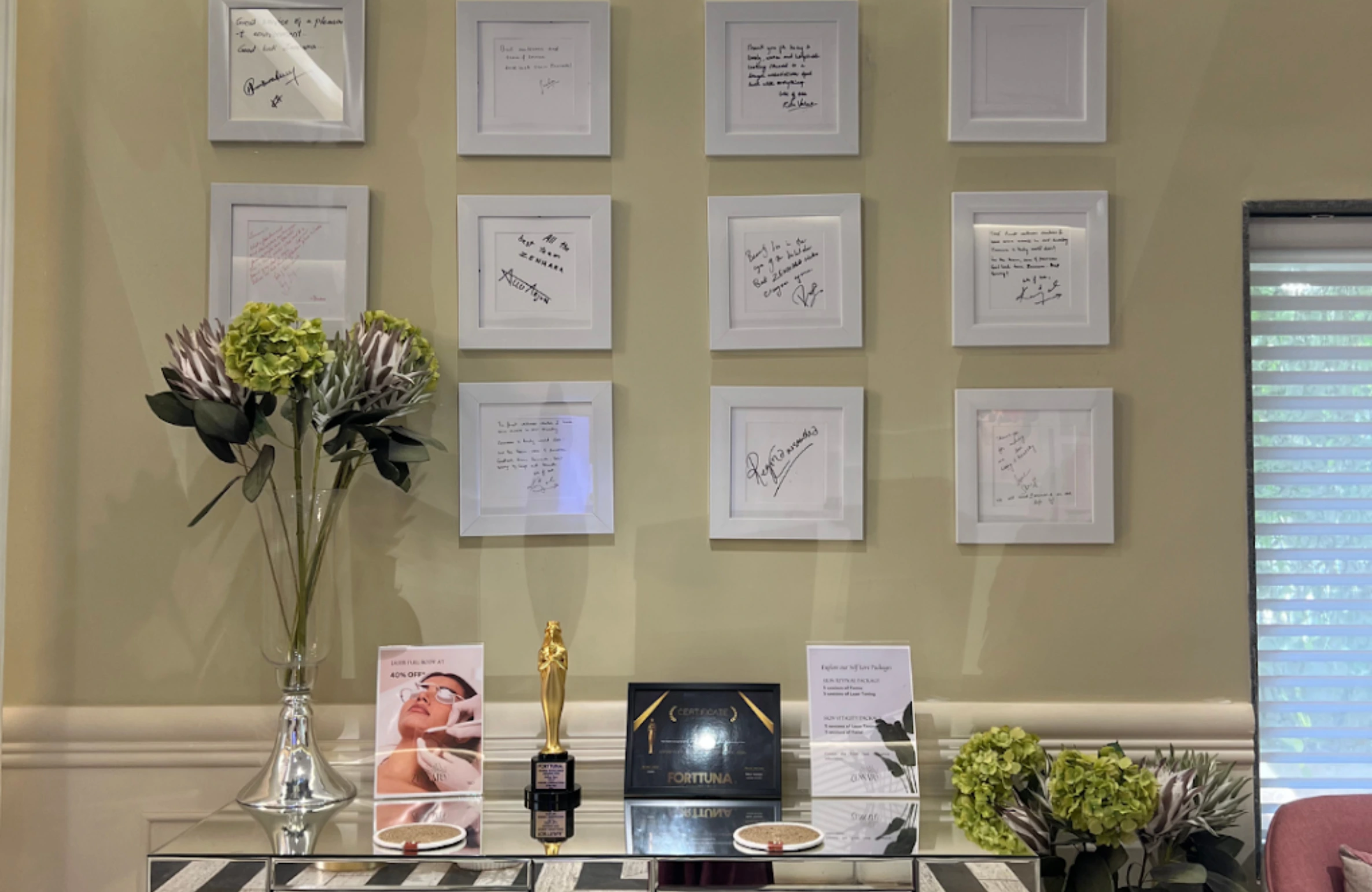 A decorated clinic wall with framed testimonials, flowers, and awards on display, highlighting the Best Skin Clinic in Jubilee Hills.